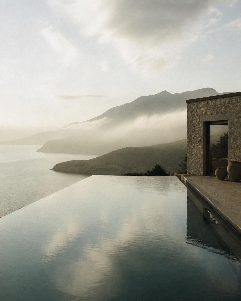 Infinity pool at a stone villa overlooking misty mountains and the sea